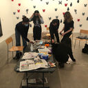 Members of Ikon Youth Programme crouch over a table littered with newspaper and magazines.