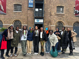 Jaz and a group of Black women pose for a photo outside of London Docklands Museum.