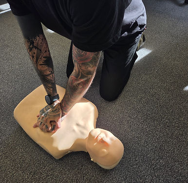 First aider practising chest compressions on a training manikin
