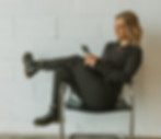 Image of Christy, Dr. Caitlin Sembach's assistant, sitting in a chair on her phone working on Sembach Chiropractic's social media.