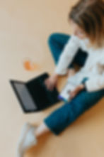 an Image of Christy, Dr. Caitlin Sembach's assistant, sitting on the floor workng on her phone and a laptop.
