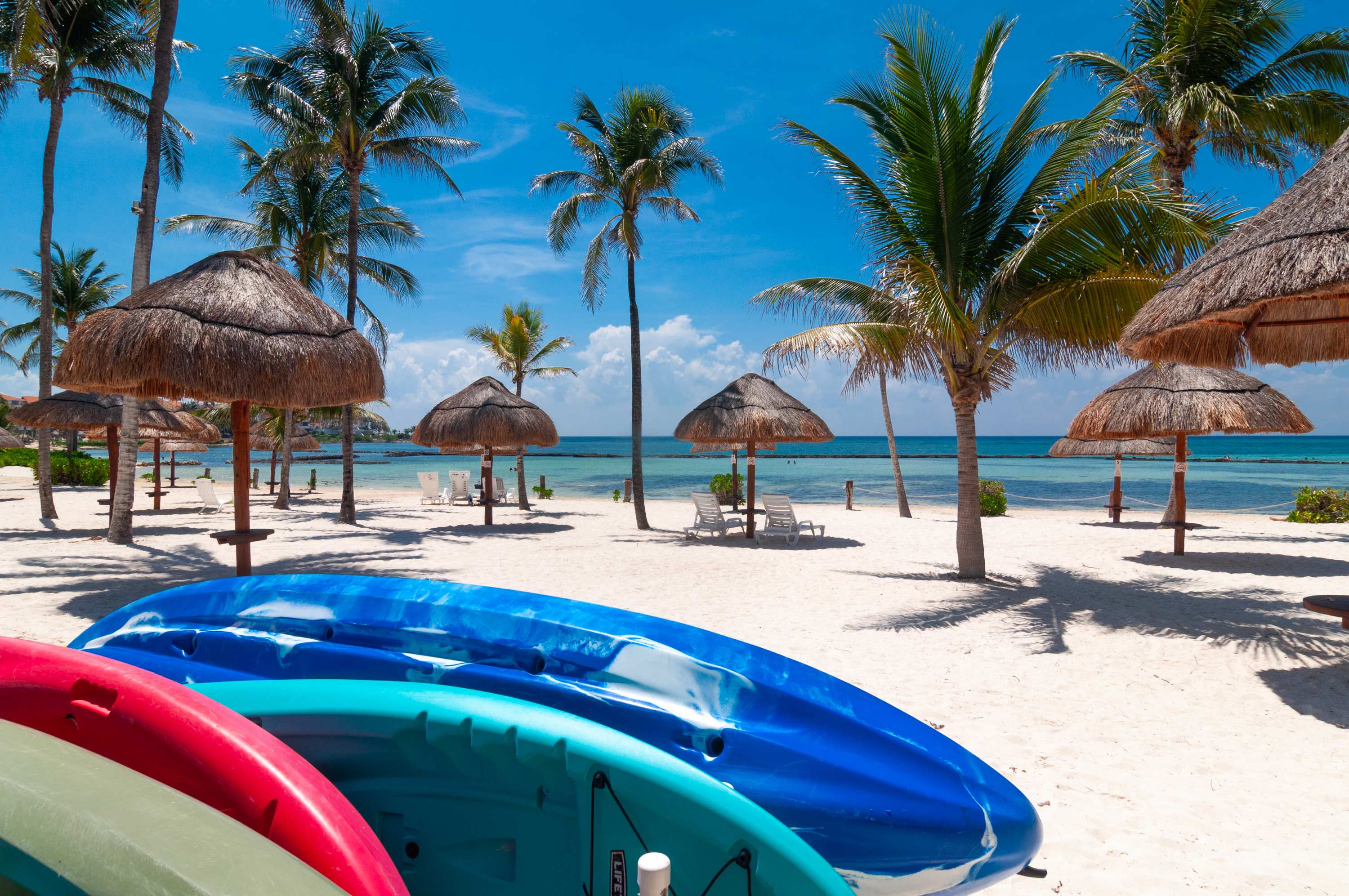 Palapas and watercraft on the beach in front of the condominium