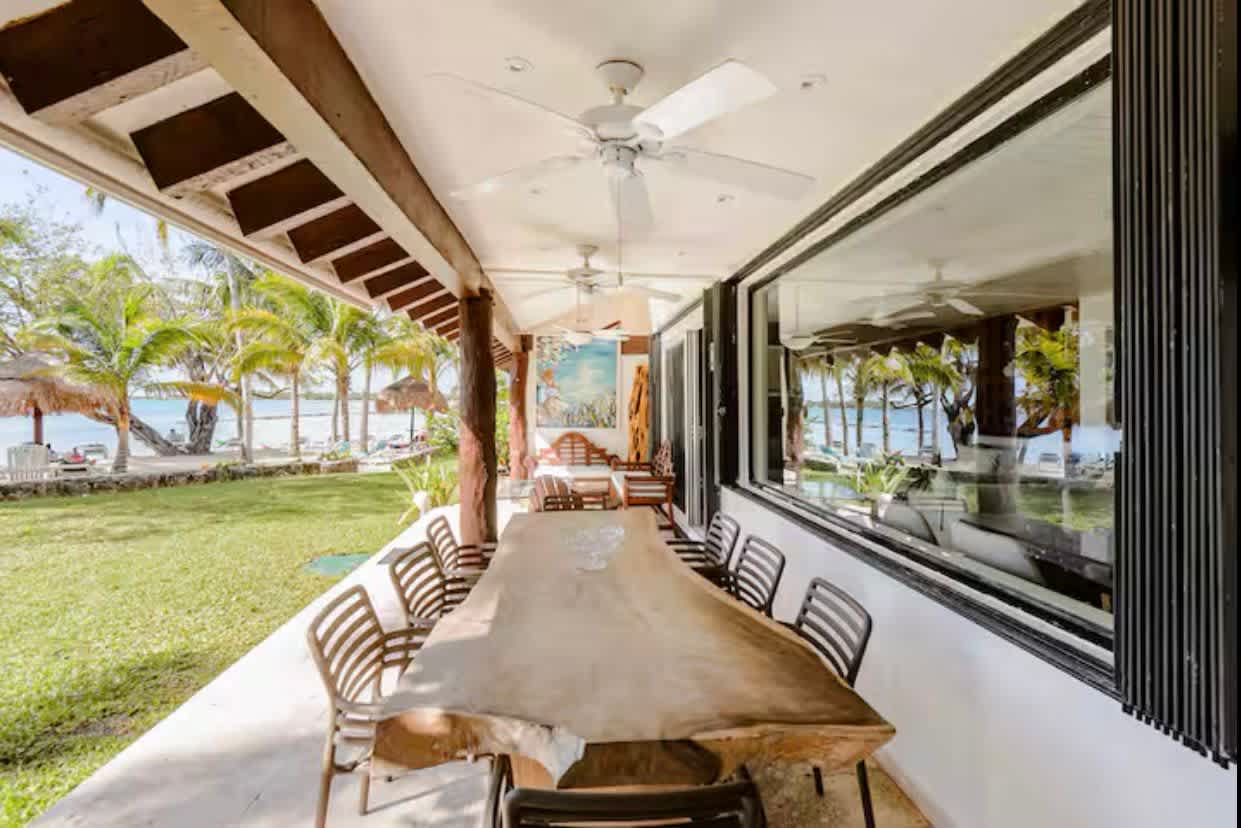 Long dining table on the covered terrace, facing the garden and the sea