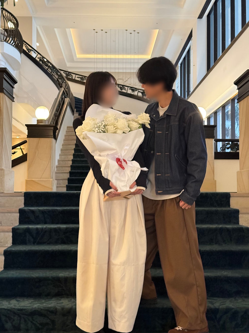 Newly engaged couple from Japan holding a white rose proposal bouquet on a Gold Coast hotel staircase