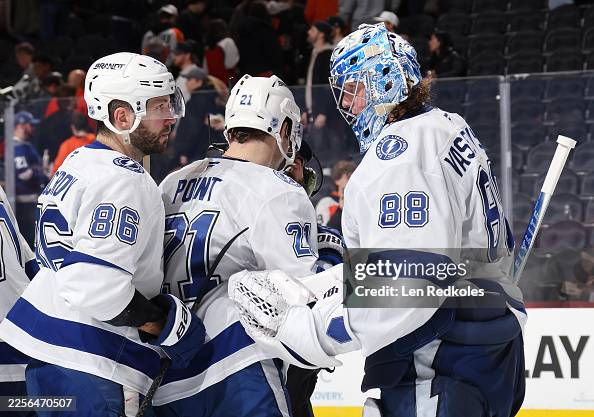 PHILADELPHIA, PENNSYLVANIA - JANUARY 10: Brayden Point #21 and Nikita Kucherov #86 of the Tampa Bay Lightning celebrate with Andrei Vasilevskiy #88 after defeating the Philadelphia Flyers 7-2 at the Xfinity Mobile Arena on January 10, 2026 in Philadelphia, Pennsylvania. (Photo by Len Redkoles/NHLI via Getty Images)