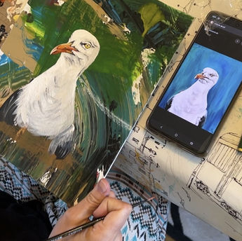 Eine Person malt eine Möwe nach einer Smartphone-Vorlage.