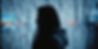 woman's silhouette looking through chain link fence