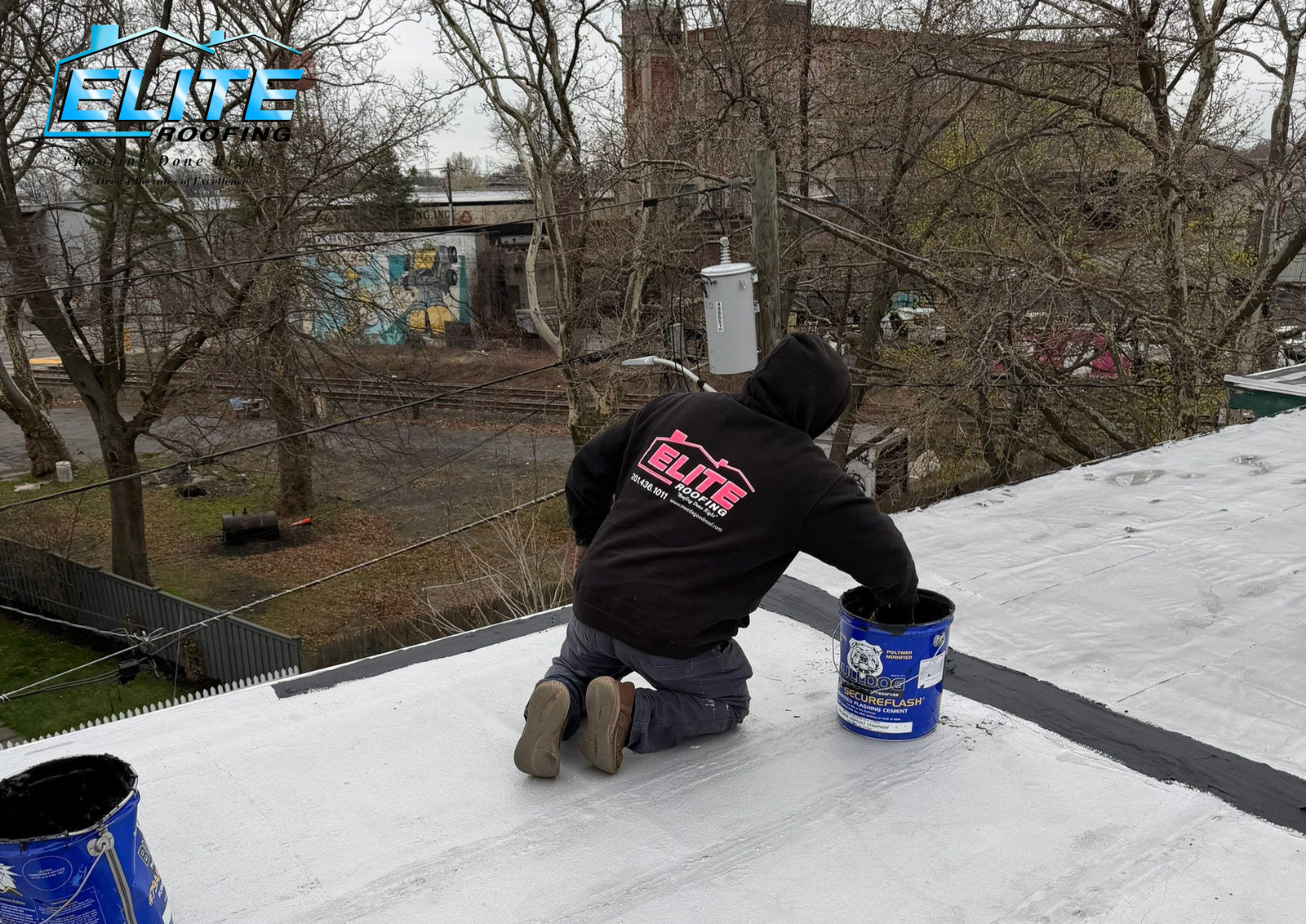 A roofer from Elite Roofing conducting a repair using roofing tar on a flat roof in Jersey City, New Jersey.