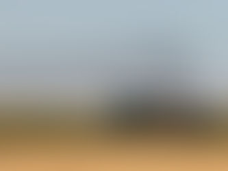 Un tracteur israélien passe dans un champ, tandis qu'au loin de la fumée s'échappe de Gaza, sous les bombes