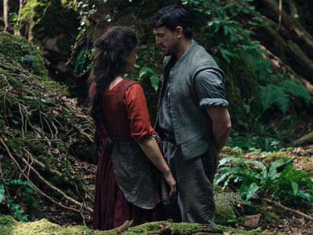 Une femme et un homme se regardant, très proches, dans la forêt.
