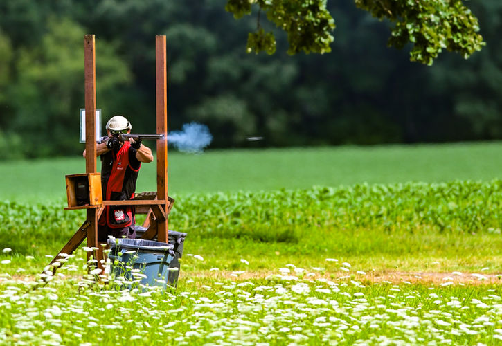 Man shooting a shotgun in flowers with smoke