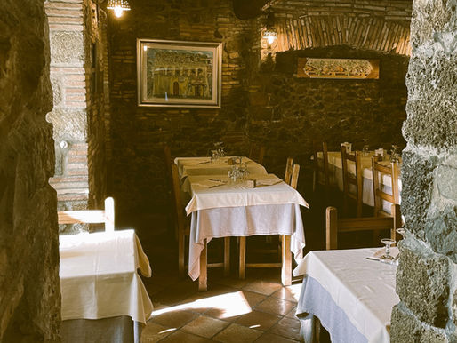 Sala interna della Tavernetta con tavoli apparecchiati e atmosfera calda e accogliente.