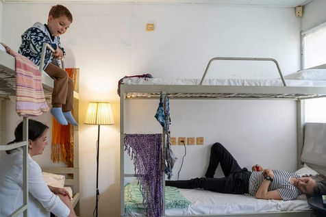 Boy on bunk bed, Dafna Talmon lying down, another woman seated in room. Participatory installation. Zumu 2023