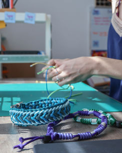 Les mains de Cindy, gérante de Baz'Art & Merveilles, qui tressent un collier pour chien en Paracord