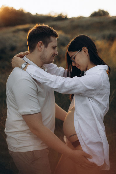 Intimes Babybauch-Fotoshooting mit zarten Berührungen bei Bonn und Köln - emotionale Schwangerschaftsfotografie im Abendlicht. 