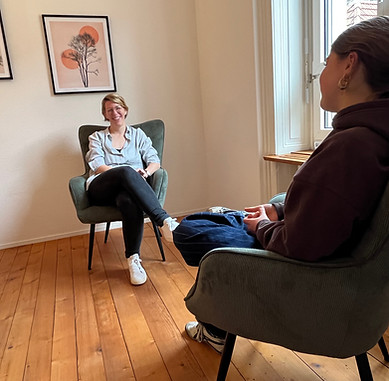 Simona Good ist mit einem Jugendlichen in einem Raum für eine psychologische Beratung. Beide sitzen sich gegenüber und lachen.