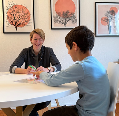 Simona Good ist im Lerncoaching mit einem jungen Menschen. Beide sitzen am Tisch, Simona lacht.