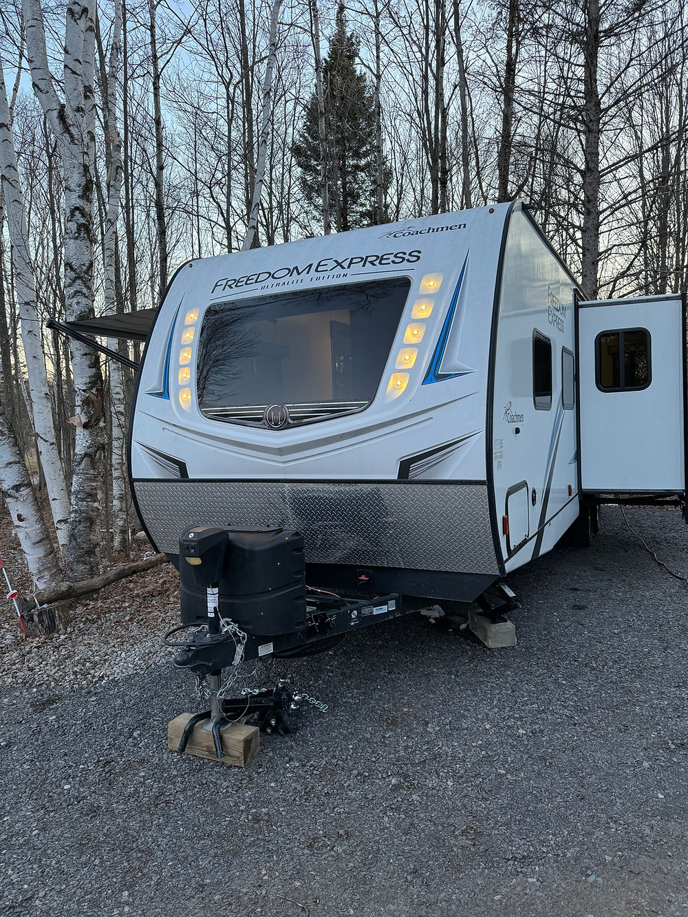 2020 Coachman Freedom Express travel trailer on gravel, door open