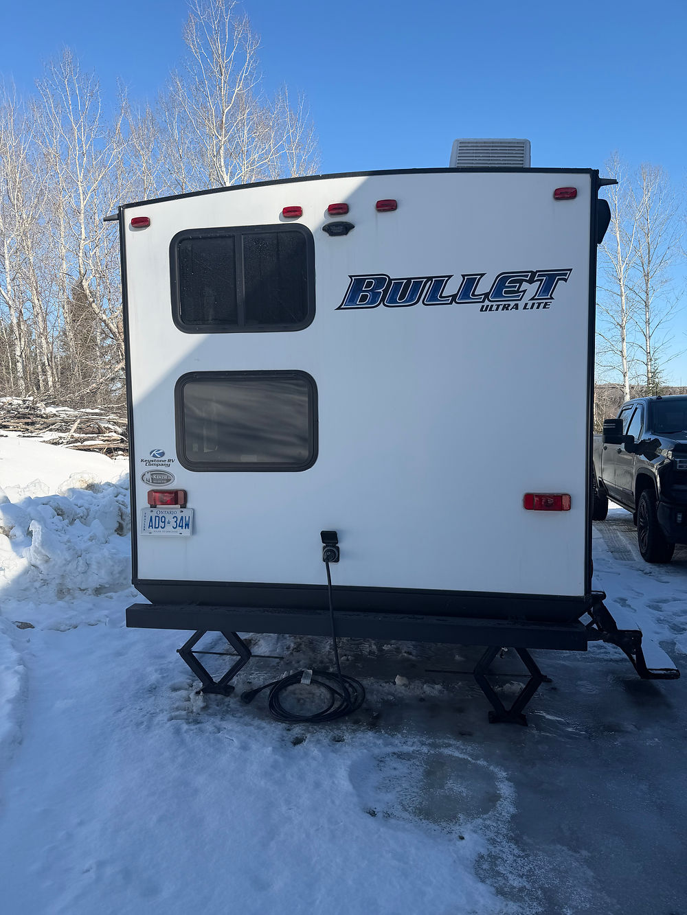 Rear exterior of a white Keystone Bullet 290BHS travel trailer