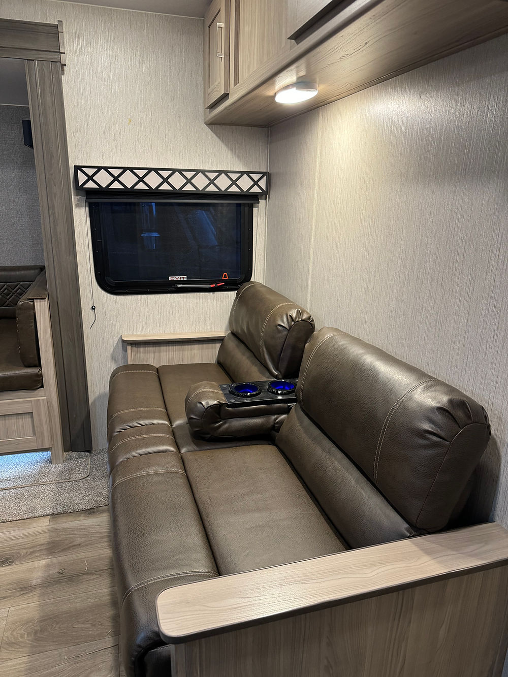 2020 Coachman Freedom Express interior, brown sofa and window.