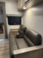 2020 Coachman Freedom Express interior, brown sofa and window.