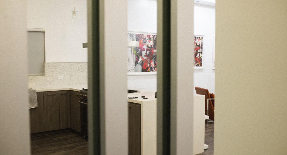 Kitchen and living space seen through a white doorway, art on the wall - JM Art Managemen
