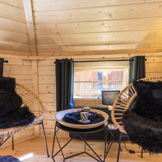 Intérieur lumineux en bois clair avec coin salon et grandes fenêtres dans le Kota finlandais.