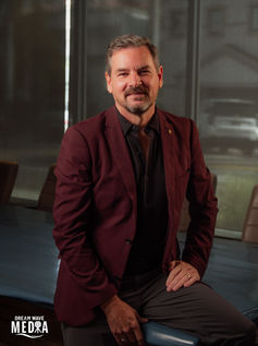 Man in red blazer smiling at camera, MEDRA, professional photography background.