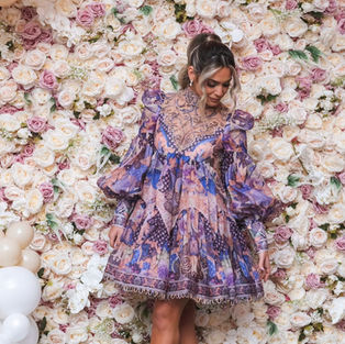 Woman posing in front of light pink flower wall