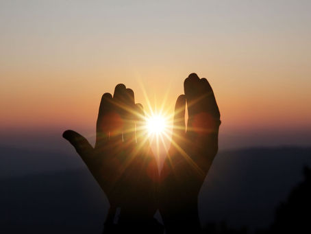 Hände halten die untergehende Sonne, als Zeichen für energetische Arbeit