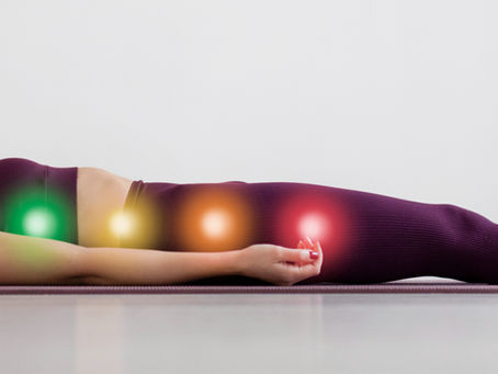 Junge Frau meditiert in Shavasana. Zeigt die sieben Hauptchakren entlang ihrer Wirbelsäule
