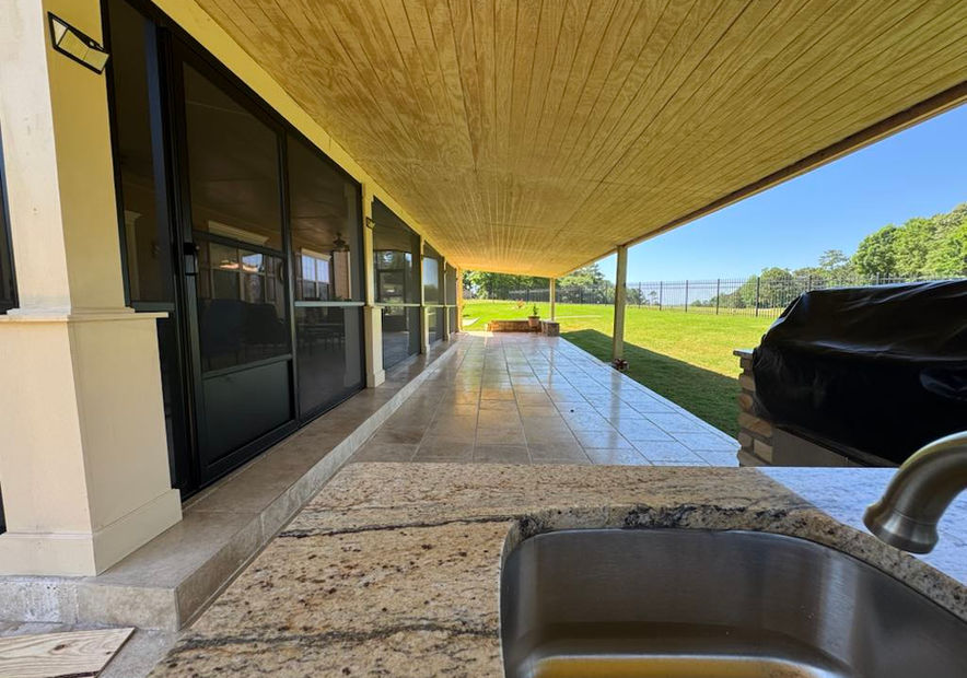 Covered patio with granite sink, grill, and open view