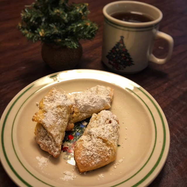 crescent shaped cookies with powdered sugar sitting on a Christmas plate