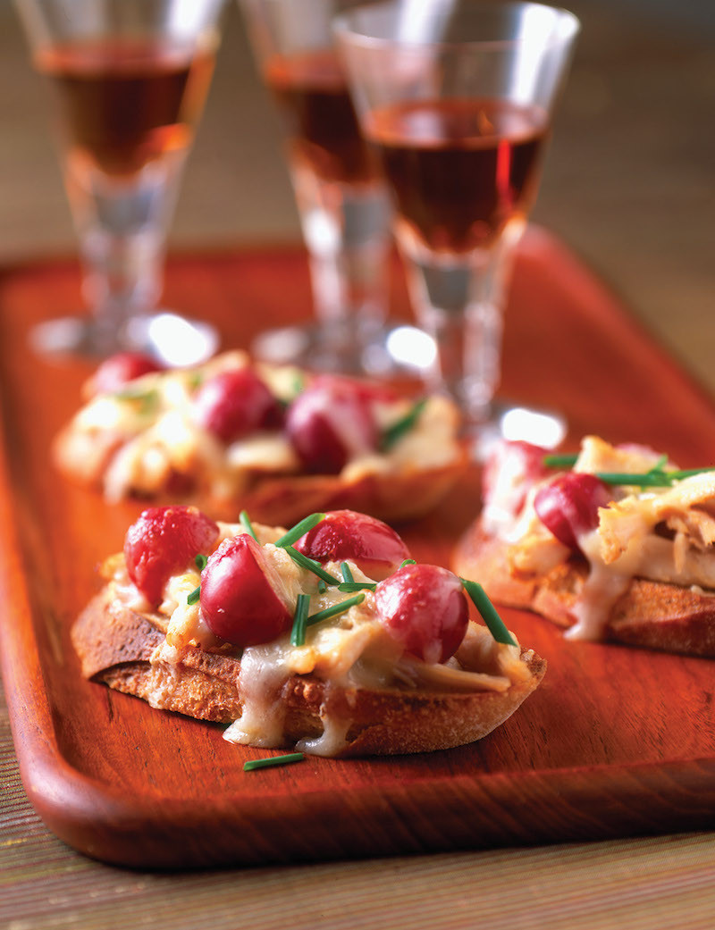 bruschetta with cheese, grapes and chicken on a board
