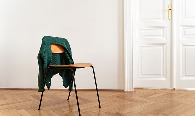 Stuhl mit grüner Jacke vor weißer Tür – Wartezimmer-Atmosphäre im Coaching