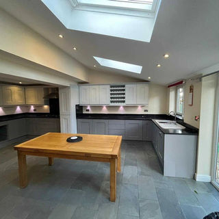 Modern grey and white kitchen with skylights and a wooden dining table