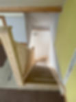 Wooden staircase in a house with unpainted walls and a vent on the ceiling.