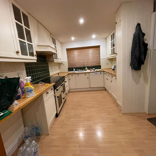 Traditional cream kitchen featuring green tiled splashback and wooden work surfaces
