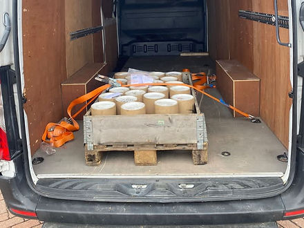 A van loaded with a wooden pallet of secured canisters and loose equipment.