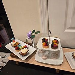 Miniature fruit tarts and cupcakes on white display stands.