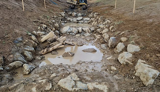 Rock-lined stream channel managing water flow during earthworks