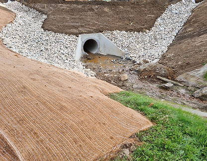 Rock-lined spillway with erosion control matting installed on earthworks site