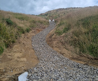 Rock-lined drainage channel installed for erosion control on steep hillside