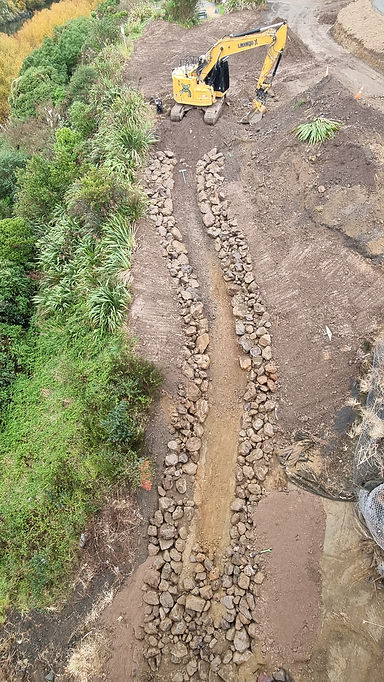 Excavator constructing rock-lined stream diversion during detailed earthworks project