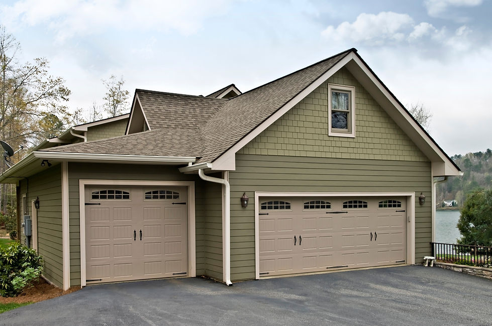 A modern, two-car garage with sage-green siding and beige doors