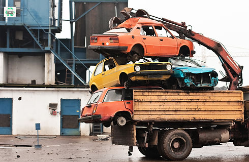 colorful cars on a flatbed truck at a scrapyard