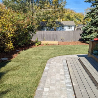 A serene backyard featuring a wooden deck overlooking a lush green lawn