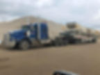 A large truck transporting a substantial load of sand on a construction site, showcasing its robust