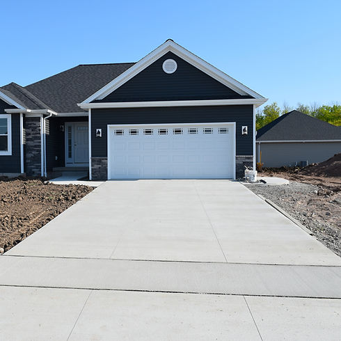 Freshly poured concrete driveway in front of a new dark grey house garage