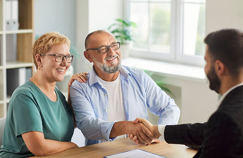 A senior couple meets their advisor in office and shaking hands